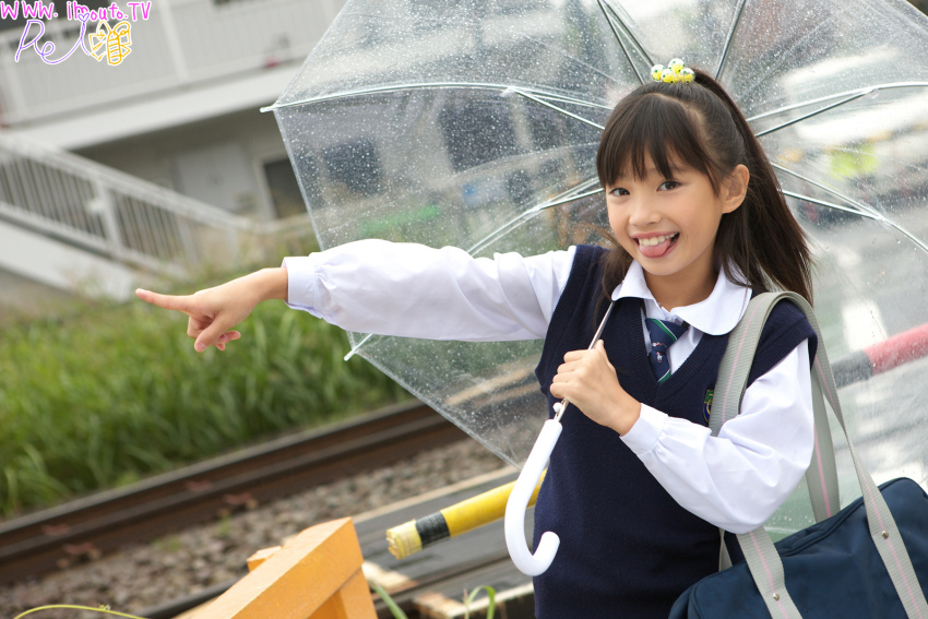 1girl black_hair brown_eyes grass highres hime_cut japanese_(nationality) kuromiya_rei long_hair looking_at_viewer outdoors photo_(medium) pointing real_life school_uniform smile sweater_vest teeth tongue train_tracks transparent transparent_umbrella umbrella