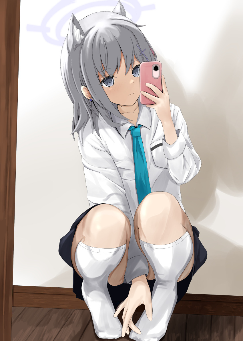 1girl absurdres animal_ear_fluff animal_ears between_legs black_skirt blue_archive blue_necktie cellphone disuto grey_eyes grey_hair hand_between_legs hand_on_own_foot highres holding holding_phone looking_at_viewer mirror_selfie necktie phone selfie shiroko_(blue_archive) shirt skirt smartphone smile squatting thighhighs white_shirt white_thighhighs wolf_ears wolf_girl wooden_floor