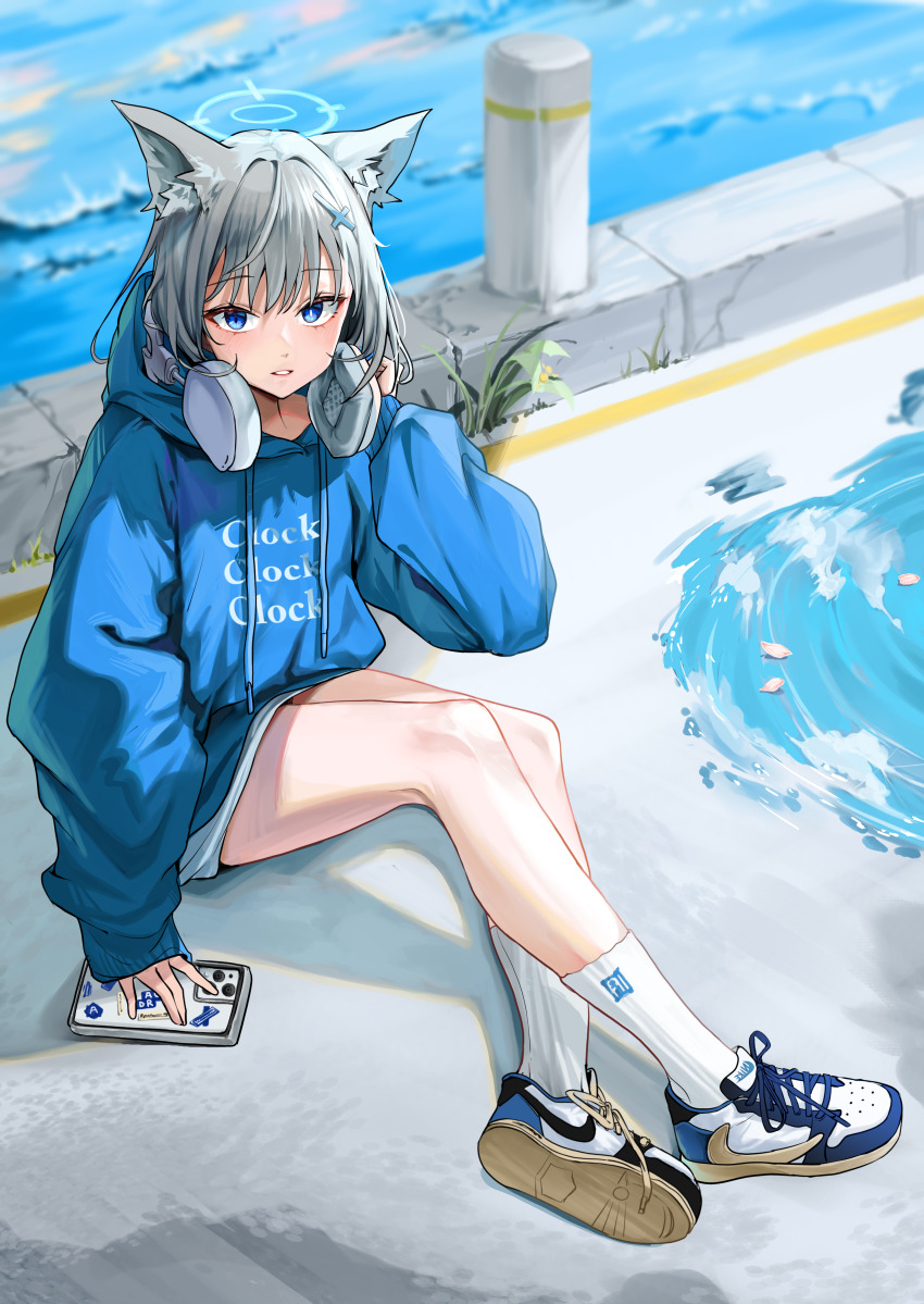 1girl absurdres air_jordan air_jordan_1 alternate_costume animal_ear_fluff animal_ears blue_archive blue_hoodie blurry blurry_background cat_ears cellphone cross_hair_ornament fragment full_body grey_hair hair_ornament halo headphones headphones_around_neck highres hood hoodie kinking knee_up long_sleeves looking_at_viewer nike_(company) open_mouth phone puddle shiroko_(blue_archive) shoes sitting smartphone sneakers socks solo travis_scott water white_socks