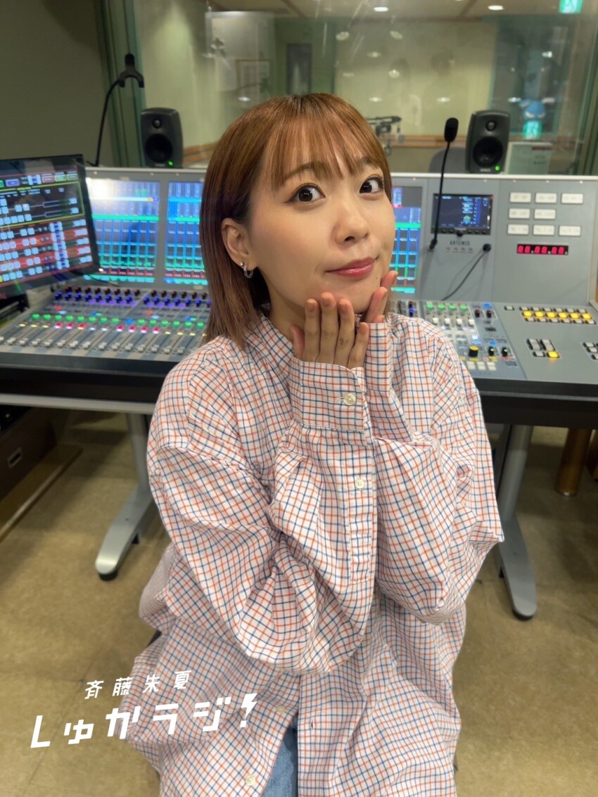 1girl brown_hair earrings indoors japanese_text jewelry looking_at_viewer photo_(medium) real_life saito_shuka shirt short_hair sitting solo voice_actor