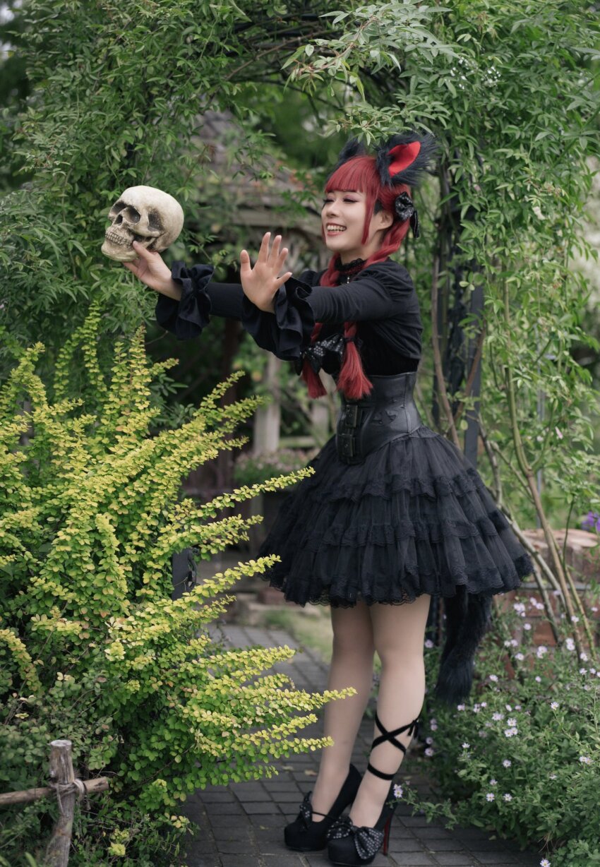 1girl animal_ears black_petticoat black_shirt black_skirt braid cat_ears cat_girl cat_tail cosplay_photo flower full_body garden gazebo goth_fashion high_heels highres holding holding_skull kaenbyou_rin leaf long_hair nakaya_th open_mouth outdoors pantyhose pergola photo_(medium) pink_flower red_hair shirt skirt skull solo standing tail teeth touhou twin_braids upper_teeth_only white_pantyhose