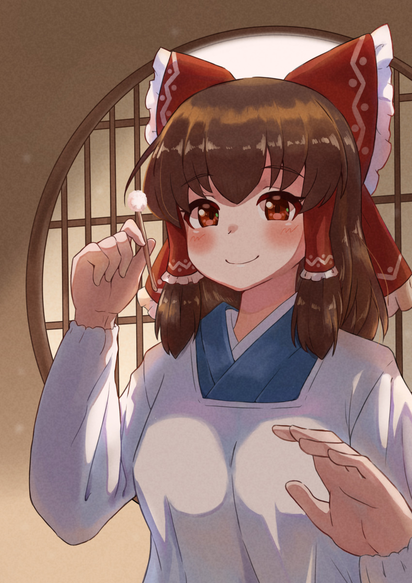 1girl absurdres alternate_costume blush bow brown_hair closed_mouth commentary_request cookie_(touhou) frilled_bow frilled_hair_tubes frills hair_bow hair_tubes hakurei_reimu highres holding indoors japanese_clothes kanna_(cookie) long_sleeves looking_at_viewer medium_hair mimikaki red_bow red_eyes smile solo touhou tsugumi_amon upper_body