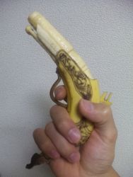  banana food fruit gun handgun highres holding photo_(medium) pistol sculpture weapon y_yamaden  rating:Sensitive score:16 user:extra_tasty