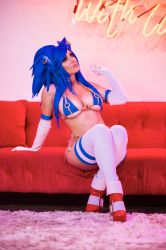  1girl animal_ears bikini blue_hair breasts carpet cosplay couch detached_sleeves earrings fake_animal_ears full_body genderswap gloves heels high_heels highres jessica_nigri jewelry large_breasts looking_to_the_side necklace on_couch photo_(medium) real_life reflective_floor ring room sitting solo sonic_(series) sonic_the_hedgehog spiked_hair swimsuit tail thighhighs 