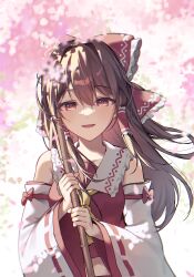  1girl absurdres ascot blurry bow brown_eyes brown_hair cherry_blossoms commentary depth_of_field detached_sleeves falling_petals frilled_bow frilled_hair_tubes frills hair_bow hair_tubes hakurei_reimu highres holding kurobikari long_hair looking_at_viewer open_mouth petals pink_petals red_bow ribbon-trimmed_sleeves ribbon_trim smile solo touhou yellow_ascot 