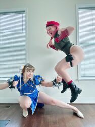  2girls ass bare_shoulders blue_eyes braid cammy_white cammy_white_(cosplay) capcom china_dress chinese_clothes chun-li chun-li_(cosplay) clenched_hands cosplay curvy double_bun dress fighting hair_bun hat highleg highleg_leotard highres huge_ass indoors jessicatalystic jumping kicking legs_apart leotard long_hair looking_at_another multiple_girls musclemommycosplay photo_(medium) pink_hair real_life shiny_clothes skindentation sleeveless smile street_fighter twin_braids wide_hips 