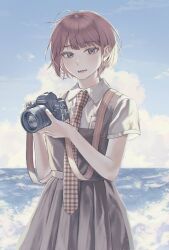  1girl :d birthday blue_sky blunt_bangs blush brand_name_imitation breast_pocket breasts brown_dress brown_eyes camera cloud collared_shirt commentary cowboy_shot cumulonimbus_cloud danganronpa_(series) danganronpa_2:_goodbye_despair day dress dslr eyelashes freckles gingham_necktie holding holding_camera horizon koizumi_mahiru looking_at_viewer loose_hair_strand lower_teeth_only messy_hair necktie ocean open_mouth outdoors parted_lips pinafore_dress pleated_dress pocket red_hair red_necktie school_uniform shirt short_hair short_sleeves sky sleeveless sleeveless_dress small_breasts smile solo standing strap taking_picture tanizaki_(tnzk555) teeth waves white_necktie white_shirt wind 