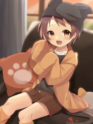  1girl beanie black_headwear black_shirt blush bow brown_eyes brown_hair brown_shorts cat_boy cat_tail child couch curtains cushion fang hat highres hood hooded_jacket jacket looking_at_viewer meranoreuka_(naokentak) open_mouth orange_jacket original shirt short_hair shorts sitting sleeves_past_wrists tail tail_bow tail_ornament window 
