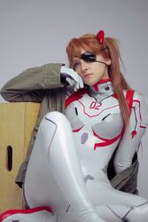 Rule 34 | 1girl, arm support, ass, blue eyes, bodysuit, brazilian (nationality), breasts, brown hair, cosplay, crossed legs, evangelion: 3.0+1.0 thrice upon a time, eyepatch, freckles, green jacket, highres, interface headset, jacket, light smile, lips, looking at viewer, memepantazis, neon genesis evangelion, photo (medium), plugsuit, rebuild of evangelion, shiny clothes, solo, souryuu asuka langley, souryuu asuka langley (cosplay), standing, twintails, two side up, white bodysuit