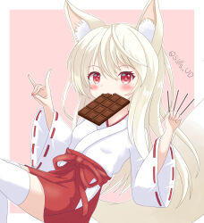 1girl animal_ear_fluff animal_ears between_fingers blush border brown_hair candy chocolate chocolate_bar commentary_request food food_in_mouth fox_ears fox_girl fox_shadow_puppet fox_tail hair_between_eyes hakama hakama_short_skirt hakama_skirt highres holding holding_food japanese_clothes kimono long_hair long_sleeves miko mouth_hold original pink_background pocky red_eyes red_hakama ribbon-trimmed_sleeves ribbon_trim sills skirt solo tail thighhighs twitter_username very_long_hair white_border white_kimono white_thighhighs wide_sleeves