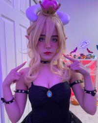 Rule 34 | 1girl, bare shoulders, black dress, blonde hair, bowsette, bowsette (cosplay), breasts, cleavage, cosplay, crown, cuban (nationality), dragon horns, dress, female focus, highres, horns, indoors, large breasts, looking at viewer, mario (series), medium hair, new super mario bros. u deluxe, nintendo, orange nails, photo (medium), pointy ears, solo, staryuuki, upper body