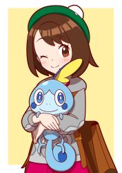 1girl ;) absurdres backpack bag blush border brown_bag brown_eyes brown_hair cardigan closed_mouth commentary_request creatures_(company) dress eyelashes game_freak gen_8_pokemon gloria_(pokemon) green_hat grey_cardigan happy hat highres holding holding_pokemon hood hood_down hooded_cardigan nintendo one_eye_closed outside_border pink_dress pokemon pokemon_(creature) pokemon_swsh smile sobble tam_o&#039;_shanter white_border yellow_background zitome_i