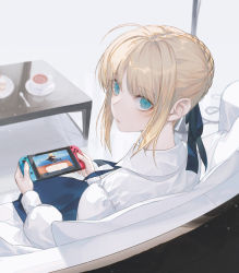 Rule 34 | 1girl, ahoge, animal crossing, aqua eyes, artoria pendragon (all), artoria pendragon (fate), blonde hair, braid, coffee table, couch, cup, dress, fate/stay night, fate (series), from behind, hair ribbon, handheld game console, holding, holding handheld game console, looking at viewer, nintendo, nintendo switch, playing, ribbon, saber (fate), saucer, sitting, solo, spoon, table, tea, teacup, wanke, white background