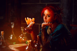 Rule 34 | 1girl, blurry, book, braid, circlet, cosplay, costume, depth of field, dress, eyeliner, eyeshadow, flask, freckles, green eyes, head rest, helly von valentine (disharmonica), indoors, jewelry, looking afar, makeup, necklace, pendant, photo (medium), red hair, robe, side braids, sitting, solo, table, the witcher (series), triss merigold, triss merigold (cosplay), upper body