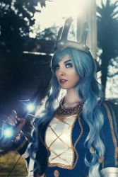 Rule 34 | 1girl, ashe (league of legends), ashe (league of legends) (cosplay), blue eyes, blue hair, bow, cosplay, crown, ice, league of legends, long hair, looking at viewer, makeup, nail polish, outdoors, photo (medium), queen, queen ashe, solo, tree, valentina kryp, weapon