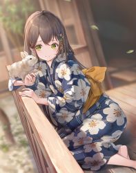 1girl absurdres animal barefoot blue_kimono blurry blurry_background blush brown_hair closed_mouth depth_of_field dutch_angle falling_leaves floral_print green_eyes hair_between_eyes hair_ornament highres holding japanese_clothes kimono leaf long_hair nogi_momoko original outdoors rabbit sash sitting smile solo