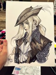 Rule 34 | 1girl, ascot, black hat, black jacket, blonde hair, bloodborne, blue shirt, collared shirt, hair behind ear, hat, hat feather, highres, holding, jacket, jewelry, lady maria of the astral clocktower, looking at viewer, mirka andolfo, necklace, photo (medium), ponytail, shirt, signature, solo, traditional media, tricorne, upper body, western comics (style), white ascot