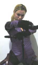 Rule 34 | blonde hair, bodysuit, capcom, cosplay, dual wielding, gloves, gun, highres, holding, jill valentine, latex, looking at viewer, non-asian, photo (medium), ponytail, resident evil, resident evil 5, simple background, solo, weapon