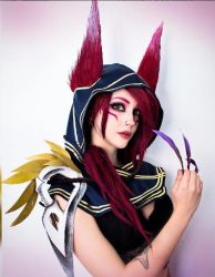 Rule 34 | 1girl, animal ears, cosplay, feathers, hood, league of legends, lipstick, long hair, looking at viewer, makeup, photo (medium), red hair, skull, solo, xayah