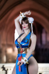 Rule 34 | 1girl, alternate costume, argentine (nationality), ass, bare hips, bare legs, bare shoulders, blue dress, blue eyes, bracelet, braid, breasts, brown hair, capcom, chun-li, chun-li (cosplay), cleavage, clenched hands, cosplay, curvy, double bun, dress, fighting stance, fingernails, hair bun, highres, jewelry, large breasts, leotard, leotard under clothes, lips, lipstick, long hair, looking at viewer, makeup, medium breasts, no bra, pelvic curtain, photo (medium), revealing clothes, shiny clothes, short dress, simple background, smile, sophie valentine, spiked bracelet, spikes, standing, street fighter, street fighter iv (series), thick thighs, thighs, wide hips