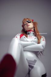 Rule 34 | 1girl, artist name, ass, blue eyes, bodysuit, brazilian (nationality), breasts, brown hair, cosplay, crossed arms, evangelion: 3.0+1.0 thrice upon a time, eyepatch, foreshortening, freckles, highres, interface headset, legs apart, lips, looking at viewer, low angle, memepantazis, neon genesis evangelion, photo (medium), plugsuit, rebuild of evangelion, shiny clothes, simple background, small breasts, solo, souryuu asuka langley, souryuu asuka langley (cosplay), standing, tsundere, twintails, two side up, white bodysuit