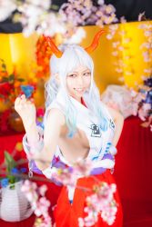 Rule 34 | 1girl, absurdres, bare arms, bare shoulders, blue hair, blurry, blurry background, blurry foreground, breasts, chain, clenched hand, cosplay, cosplay photo, cuffs, curled horns, flower, gradient hair, green hair, grin, hakama, hakama skirt, hand on own hip, hand up, highres, horns, japanese clothes, kataginu, long hair, looking to the side, multicolored hair, multicolored horns, no bra, one piece, oni, orange eyes, orange horns, photo (medium), red horns, rope, shackles, shimenawa, sideboob, skirt, smile, solo, standing, white hair, yamato (one piece), yamato (one piece) (cosplay)