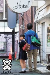Rule 34 | 1girl, asian, backpack, bag, black hair, from behind, height difference, kawashima kurumi, looking at viewer, looking back, outdoors, photo (medium), randoseru, school uniform, skirt, twintails, walking