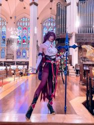Rule 34 | 1girl, anaeliccosplay, bare shoulders, black footwear, boots, christianity, church, commentary, cosplay photo, elbow gloves, english commentary, full body, genshin impact, gloves, hair over one eye, high heel boots, high heels, highres, holding, holding polearm, holding weapon, indoors, looking at viewer, pantyhose, photo (medium), polearm, purple hair, purple pantyhose, rosaria (genshin impact), solo, spear, stained glass, weapon