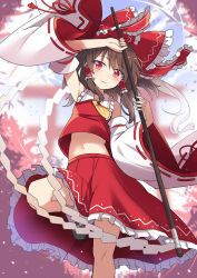 Rule 34 | 1girl, ascot, blurry, blurry background, blush, bow, brown hair, closed mouth, detached sleeves, e.o., gohei, hair bow, hair tubes, hakurei reimu, highres, holding, looking at viewer, medium hair, midriff, navel, petals, red bow, red eyes, red skirt, skirt, smile, solo, torii, touhou, wide sleeves, yellow ascot