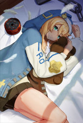 Rule 34 | 1boy, absurdres, androgyne symbol, bike shorts, bike shorts under skirt, black skirt, blonde hair, blue jacket, bridget (guilty gear), chain, closed mouth, feathers, feet out of frame, from above, from side, green eyes, guilty gear, guilty gear strive, hair between eyes, highres, holding, holding stuffed toy, hood, hood up, hooded jacket, jacket, kuronouka, light smile, long sleeves, looking at viewer, lying, miniskirt, on bed, on side, pleated skirt, skirt, stuffed animal, stuffed toy, teddy bear, trap, white feathers, yo-yo, zipper