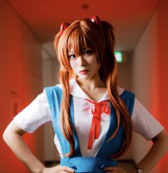 Rule 34 | blue eyes, bow, collarbone, collared shirt, cosplay, cosplay photo, cowboy shot, glico happy, hands on own hips, highres, looking at viewer, neon genesis evangelion, photo (medium), red background, red bow, red hair, red lips, shirt, souryuu asuka langley, souryuu asuka langley (cosplay), tagme, upper body
