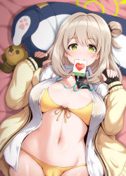 Rule 34 | 1girl, bed sheet, bikini, bikini under clothes, black gloves, blue archive, blush, breasts, breasts apart, brown hair, cleavage, cowboy shot, fingerless gloves, from above, front-tie bikini top, front-tie top, gloves, green eyes, groin, hair bun, halo, hands up, hiraga daidai, id card, jacket, large breasts, long hair, long sleeves, looking at viewer, lying, mouth hold, navel, nonomi (blue archive), nonomi (swimsuit) (blue archive), on back, one side up, open clothes, open jacket, single hair bun, sleeves past wrists, solo, stomach, stuffed animal, stuffed toy, sweater, swimsuit, swimsuit under clothes, teddy bear, yellow bikini