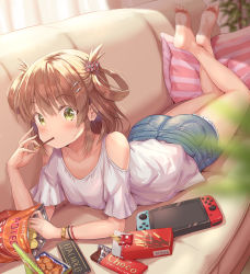 Rule 34 | 1girl, bare shoulders, barefoot, blouse, blush, bracelet, breasts, brown hair, candy, chips (food), chocolate, chocolate bar, collarbone, couch, crossed legs, denim, denim shorts, eating, food, green eyes, hair ornament, hair rings, hairpin, handheld game console, highres, hirokazu (analysis-depth), jewelry, looking at viewer, lying, nintendo switch, no shoes, on stomach, pillow, pocky, potato chips, princess connect!, rino (princess connect!), rino (real) (princess connect!), shirt, shorts, small breasts, soles, solo, the pose, two side up, white shirt, wristband