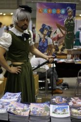 Rule 34 | asian, beard, black bow, black bowtie, blurry, blurry background, bow, bowtie, closed mouth, commentary request, convention, cosplay, cosplay photo, crossdressing, depth of field, facial hair, goatee, green skirt, green vest, hairband, hand on own hip, highres, holding, holding sword, holding weapon, konpaku youmu, konpaku youmu (cosplay), looking at viewer, male focus, manga (object), manly, mitsuki yuuya, photo (medium), puffy short sleeves, puffy sleeves, scabbard, sheath, short sleeves, skirt, solo, standing, sword, table, touhou, vest, weapon, white hair