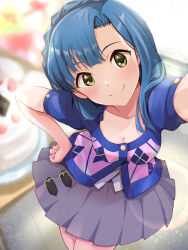 Rule 34 | 1girl, argyle, argyle clothes, argyle shirt, arm up, blue hair, blurry, blurry background, blush, braid, breasts, cake, cleavage, closed mouth, collarbone, dot nose, food, from above, grey skirt, hand on own hip, highres, idolmaster, idolmaster million live!, idolmaster million live! theater days, indoors, lens flare, looking at viewer, medium breasts, nanao yuriko, pleated skirt, selfie, shinomiyabi, short hair, short sleeves, skirt, smile, solo, standing, table, two-tone shirt, yellow eyes