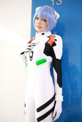 Rule 34 | 1girl, asian, ayanami rei, blue hair, color contacts, cosplay, cowboy shot, hairpods, highres, looking at viewer, namada, neon genesis evangelion, photo (medium), plugsuit, red eyes, short hair, solo, standing