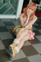 Rule 34 | 1girl, belt, boots, bracelet, cosplay, female focus, final fantasy, final fantasy xiii, full body, jewelry, midriff, necklace, oerba dia vanille, oerba dia vanille (cosplay), on floor, photo (medium), pink shirt, shirt, sitting, skirt, solo, twintails