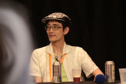 Rule 34 | 1boy, alcohol, beer, cup, glasses, green shirt, hat, lanyard, looking away, male focus, photo (medium), real life, shirt, solo, table, zun