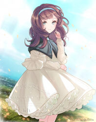 1girl blue_brooch blue_eyes blue_hairband brooch brown_hair capelet closed_mouth day dress frilled_dress frills grass green_capelet hairband hand_up ich. jewelry long_hair long_sleeves looking_at_viewer looking_to_the_side medium_dress ocean original outdoors smile solo white_dress