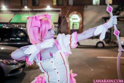 Rule 34 | 1girl, bow, bow (weapon), cosplay, dress, holding, holding bow (weapon), holding weapon, kaname madoka, kaname madoka (cosplay), kaname madoka (magical girl), lana rain, magical girl, mahou shoujo madoka magica, night, outdoors, photo (medium), pink eyes, pink hair, twintails, weapon