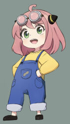 Rule 34 | 1girl, :d, ahoge, anya (spy x family), blue overalls, child, commentary, full body, goggles, goggles on head, green background, green eyes, hairpods, hands on own hips, highres, legs apart, nekonosuke, open mouth, overalls, peanut, pink hair, shirt, simple background, smile, solo, spy x family, symbol-only commentary, teeth, upper teeth only, yellow shirt