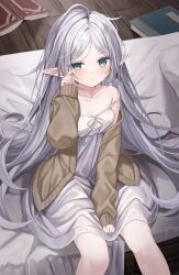 Rule 34 | 1girl, bare shoulders, between legs, blush, book, brown sweater, collarbone, elf, frieren, green eyes, grey hair, hand between legs, highres, indoors, long hair, long sleeves, looking at viewer, messy hair, nightgown, on bed, parted lips, pointy ears, rubbing eyes, shouu-kun, sidelocks, sitting, sleeves past wrists, solo, sousou no frieren, strap slip, sweater, thick eyebrows, very long hair, white nightgown