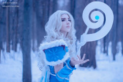 Rule 34 | 1girl, aqua eyes, armor, blonde hair, blue cloak, blue dress, blue eyes, cloak, cosplay, crystal, crystal maiden, crystal maiden (cosplay), dota (series), dota 2, dress, eyelashes, eyeliner, eyeshadow, forest, fur trim, gloves, knees, lips, long hair, makeup, nature, nose, outstretched hand, photo (medium), self-upload, signature, snow, snowing, solo, staff, standing, winter