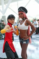 Rule 34 | 2girls, asian, black hair, chinese clothes, cosplay, crop top, dark-skinned female, dark skin, hands on own hips, midriff, multiple girls, navel, photo (medium), pink hair, poison (final fight), poison (final fight) (cosplay), short shorts, shorts, street fighter
