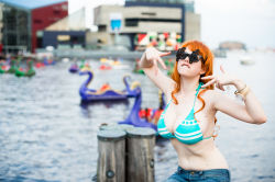 Rule 34 | 1girl, baltimore, bikini, bikini top only, blurry, bracelet, breasts, cleavage, cosplay, denim, depth of field, flaming-goddess, glasses, huge breasts, jeans, jewelry, large breasts, nami (one piece), nami (one piece) (cosplay), one piece, orange hair, outdoors, pants, photo (medium), sitting, solo, swimsuit, water