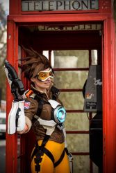 Rule 34 | 1girl, ardsami, bodysuit, brown hair, city, cosplay, goggles, gun, leggings, open mouth, outdoors, overwatch, overwatch 1, phone, photo (medium), short hair, smile, spandex, tracer (overwatch), vest, weapon