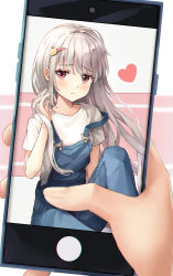 Rule 34 | 1girl, absurdres, bekso, blush, closed mouth, frown, hair ornament, hairclip, hand in own hair, hand up, heart, highres, holding, holding phone, long hair, looking at viewer, orange eyes, original, overalls, phone, shirt, short sleeves, silver hair, solo, strap slip, white shirt