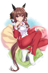 1girl absurdres animal_ears ball braid braided_hair_rings brown_hair commentary_request ear_covers ear_ornament evefly_megane_p full_body gentildonna_(umamusume) hair_rings highres horse_ears horse_girl horse_tail jacket long_hair long_sleeves no_shoes pants pillow red_eyes red_jacket red_pants simple_background sitting socks solo tail tracen_training_uniform track_jacket track_pants umamusume white_background white_socks