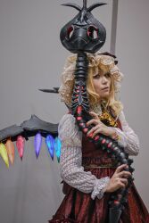 Rule 34 | 1girl, adapted costume, blonde hair, closed mouth, cosplay photo, cowboy shot, flandre scarlet, glowing, glowing weapon, glowing wings, grey background, hat, highres, holding, holding polearm, holding weapon, laevatein (touhou), long sleeves, looking at viewer, mametacos, medium hair, mob cap, multicolored wings, nail polish, photo (medium), polearm, red nails, red skirt, red vest, simple background, skirt, skirt set, solo, touhou, vest, weapon, white hat, wings