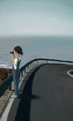 Rule 34 | 1girl, absurdres, black hair, blue overalls, camera, commentary, cowltori, english commentary, from side, grass, guard rail, hair tie, highres, holding, holding camera, lanyard, low ponytail, medium hair, ocean, original, overalls, road, scenery, shadow, shirt, shoes, short sleeves, sneakers, standing, street, water, white footwear, white shirt, wide shot